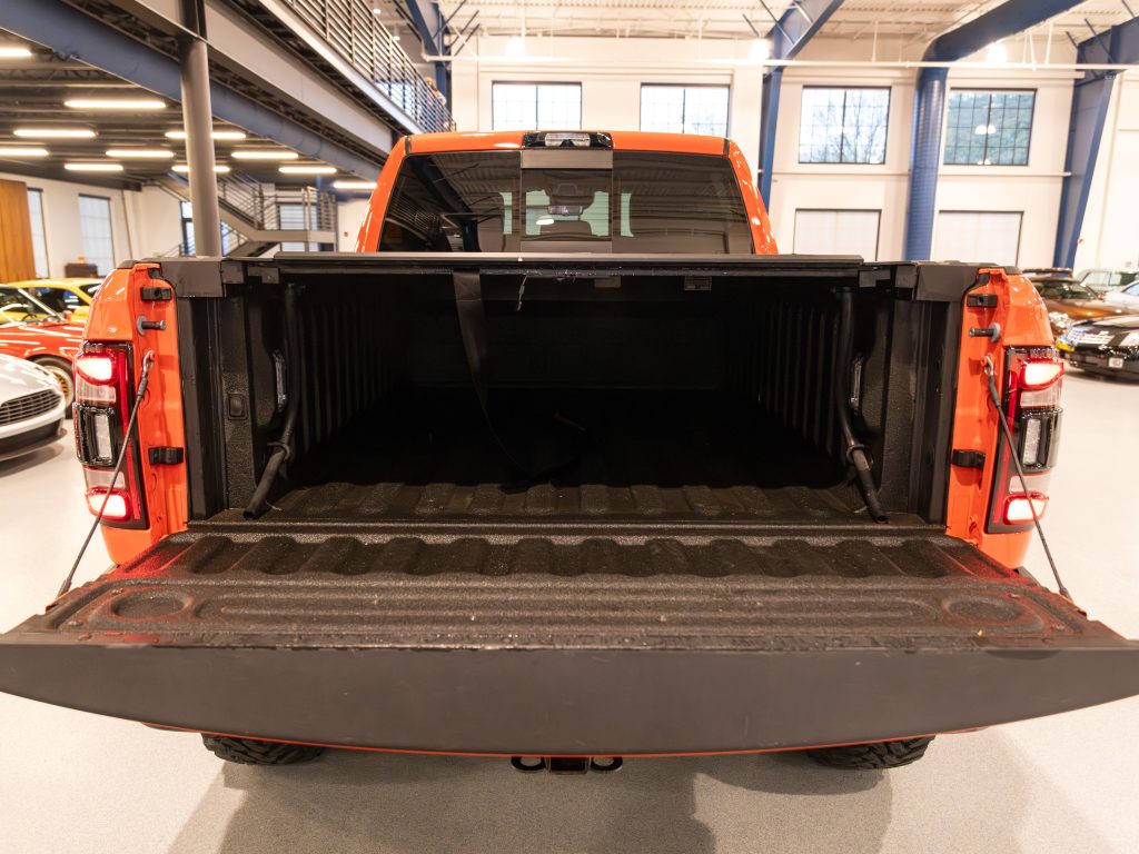 Rear view of an orange pickup truck with an open tailgate and empty bed. - Monarch Showroom