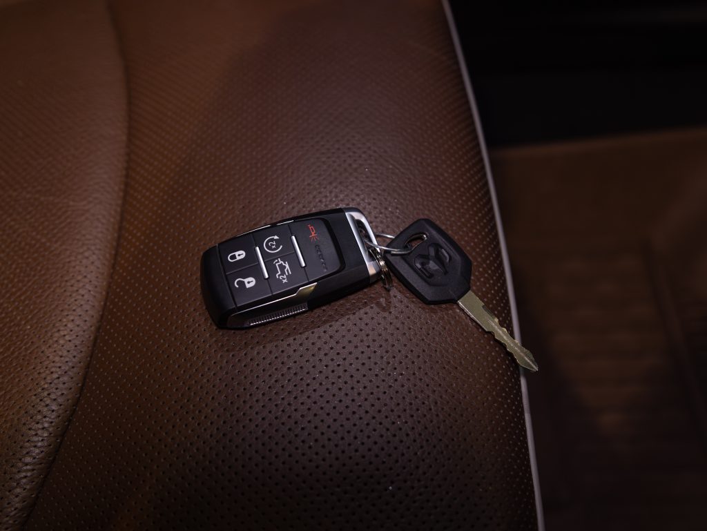 A car key with an integrated remote control is placed on a brown leather surface. - Monarch Showroom