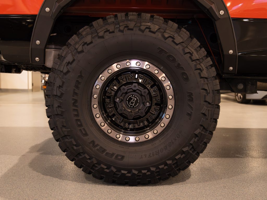 Black off-road vehicle wheel with toyo tire on display. - Monarch Showroom