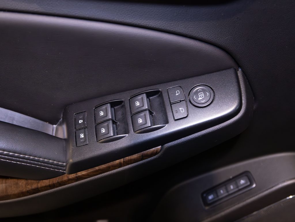 Car door interior showing window control buttons, lock switches, and a mirror adjustment knob on a black panel. - Monarch Showroom
