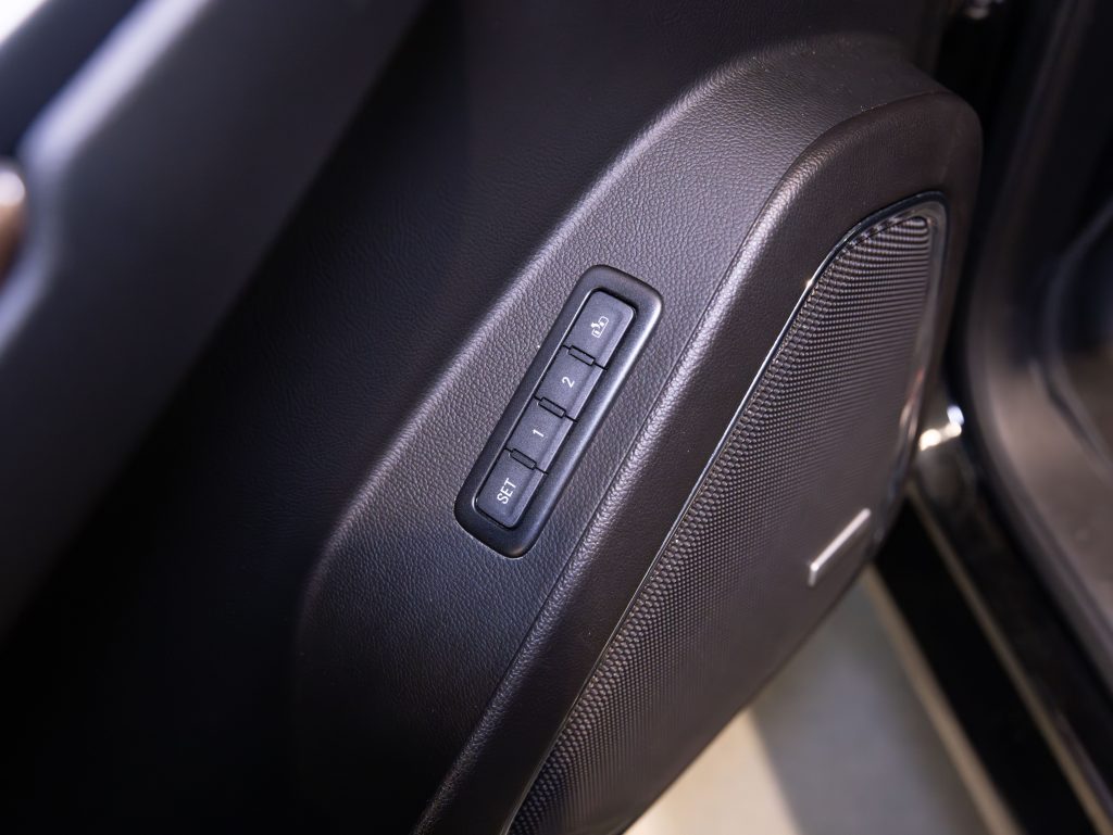 Close-up of car door interior featuring speaker and three memory seat buttons labeled "SET," "1," and "2" on a dark panel. - Monarch Showroom