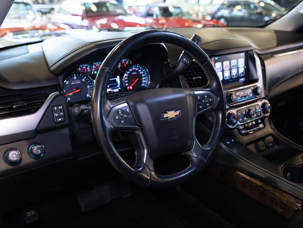 Interior view of a car featuring a Chevrolet steering wheel, dashboard with gauges, and a touchscreen display. Several buttons and controls are visible. - Monarch Showroom