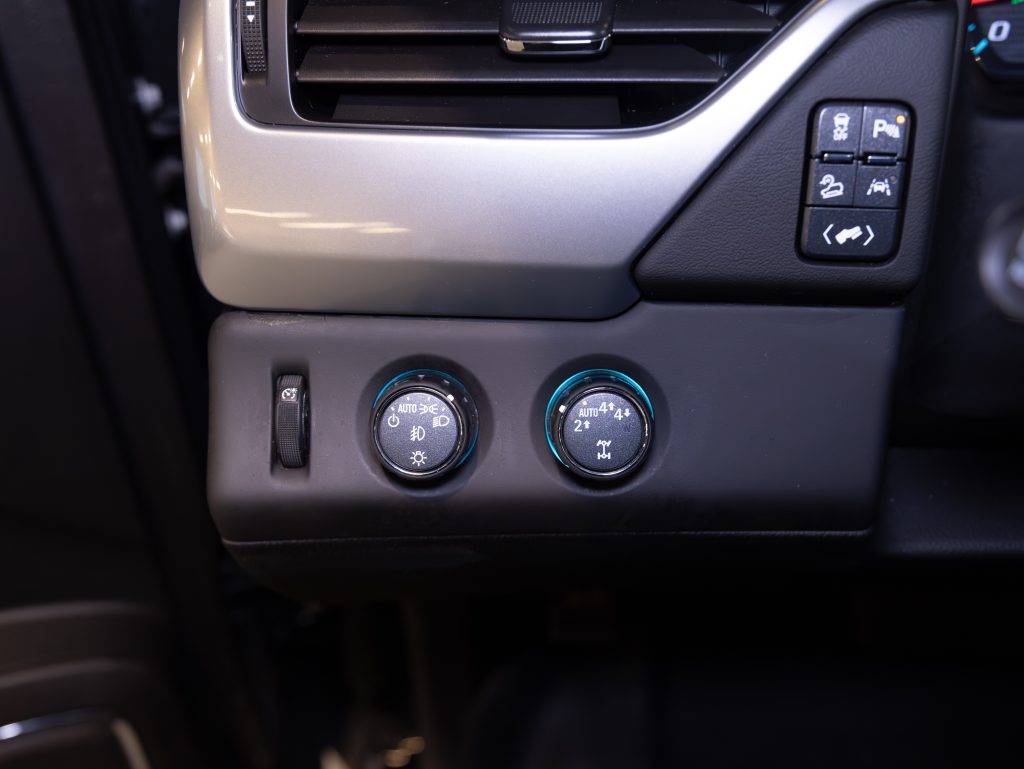 Close-up of a car's climate control knobs and buttons. Two dials adjust temperature settings, with additional buttons nearby for other controls. Air vent visible above. - Monarch Showroom