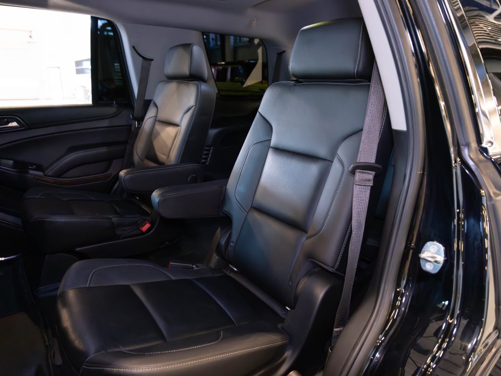 Interior of a vehicle showing two black leather seats with armrests and seatbelts, arranged in a spacious cabin. - Monarch Showroom
