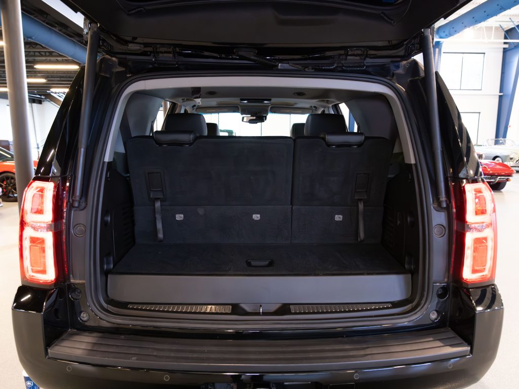 Open rear view of an SUV with the back hatch lifted, showing the spacious cargo area and folded third-row seats, in a garage setting. - Monarch Showroom