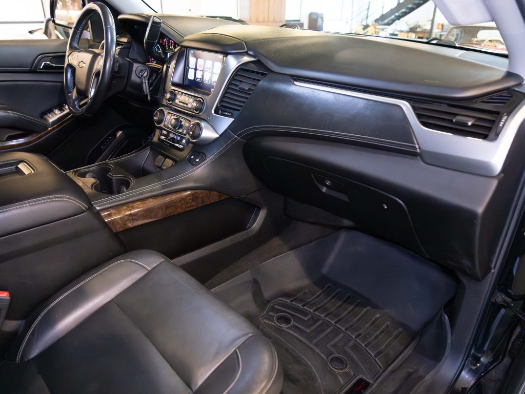 Interior of a car showing the dashboard, touchscreen, steering wheel, leather seats, and wood accents. - Monarch Showroom