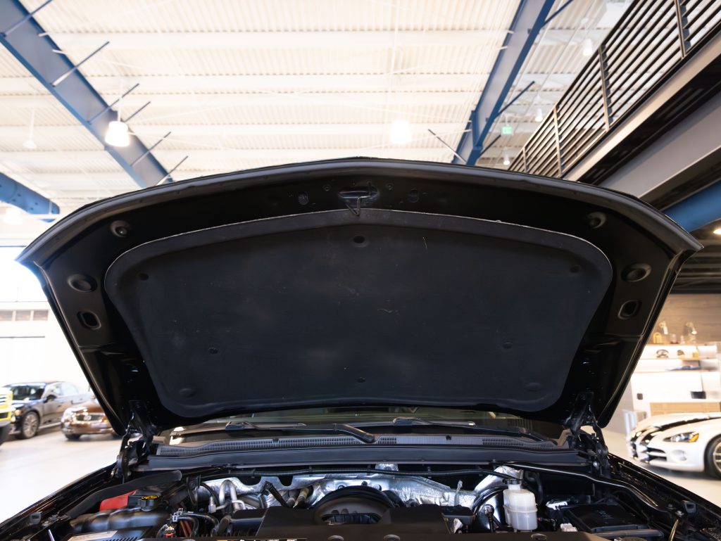 Car hood open, displaying engine components inside a well-lit automotive showroom. - Monarch Showroom