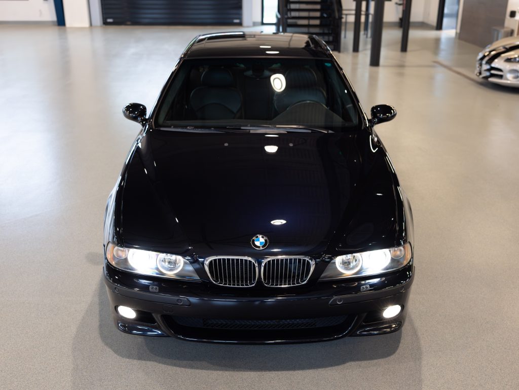 Front view of a black BMW sedan parked indoors on a light gray floor, with headlights and grille visible. - Monarch Showroom